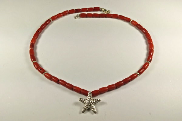 Eine leuchtend rote Kette aus Baumkoralle. Durch die eingearbeiteten Silber-Teilchen in Linsenform liegt die Kette schön rund. Der Seestern in der Mitte macht diese Kette zu einem Hingucker, nicht nur am Strand