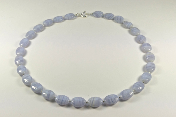 Elegante Kette aus hellblauem Calcedon. Die ovalen Perlen mit der typischen Streifen-Maserung sind mit kleinen Silberkügelchen getrennt. Z.Z gibt eine fast identische, aber mit kleinen blau-schwarzen Süsswasserperlen.