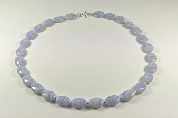 Elegante Kette aus hellblauem Calcedon. Die ovalen Perlen mit der typischen Streifen-Maserung sind mit kleinen Silberkügelchen getrennt. Z.Z gibt eine fast identische, aber mit kleinen blau-schwarzen Süsswasserperlen.